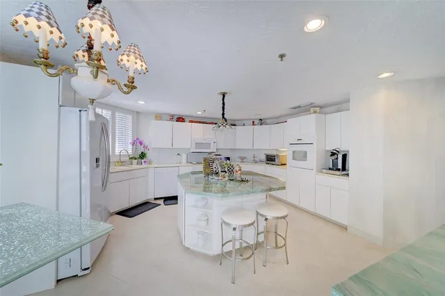 a kitchen with a dining table cabinets stainless steel appliances and a chandelier