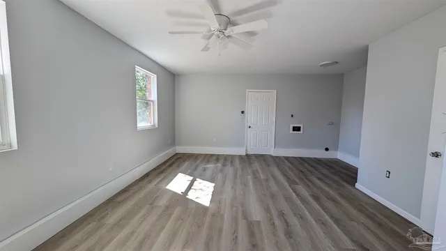 a view of empty room with wooden floor and fan