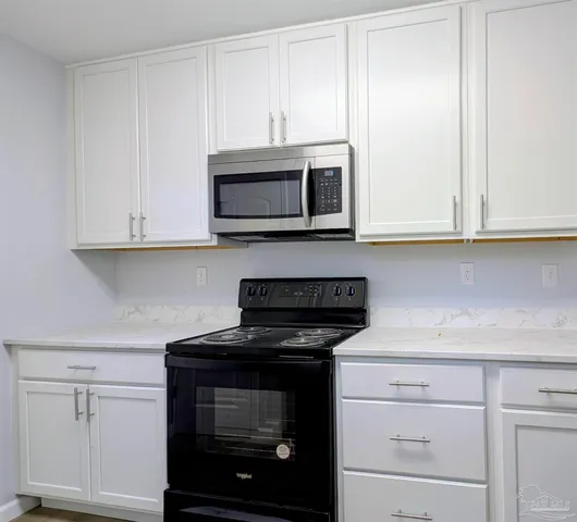 a kitchen with granite countertop white cabinets and stainless steel appliances