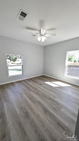 an empty room with wooden floor ceiling fan and window