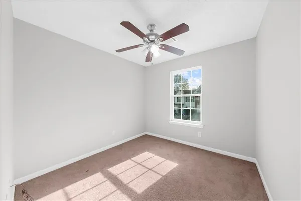 a view of an empty room with window and ceiling fan