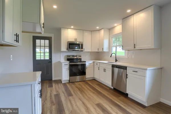 a kitchen with stove a sink and dishwasher a refrigerator with wooden floor