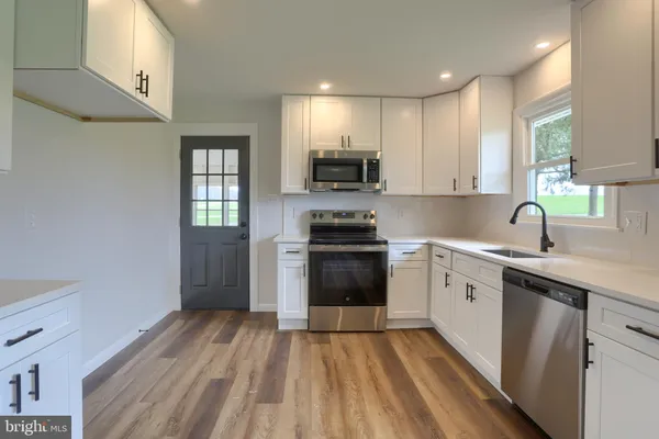 a kitchen with granite countertop a sink cabinets and stainless steel appliances