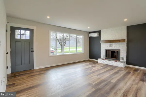 an empty room with wooden floor fireplace and windows
