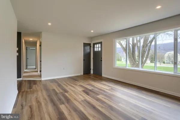 a view of an empty room with a window and wooden floor