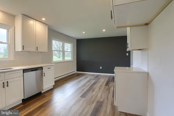 a kitchen with granite countertop white cabinets and wooden floor