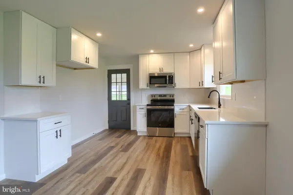 a kitchen with a sink a counter top space stainless steel appliances and cabinets