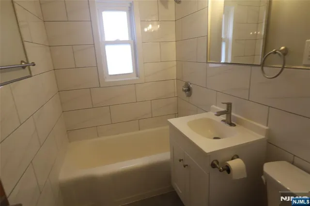 a bathroom with a sink and mirror with bathtub