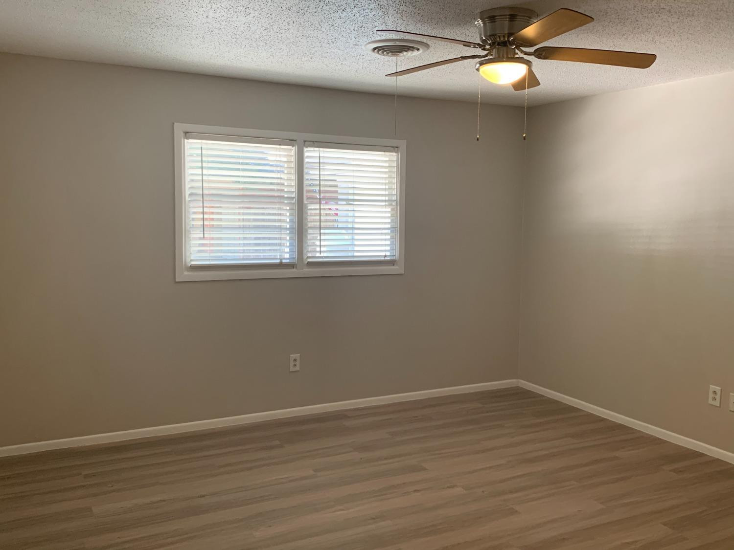4316 58th Street, Unit A Lubbock, TX 79413 - Photo 6 of 10 an empty room with wooden floor fan and windows