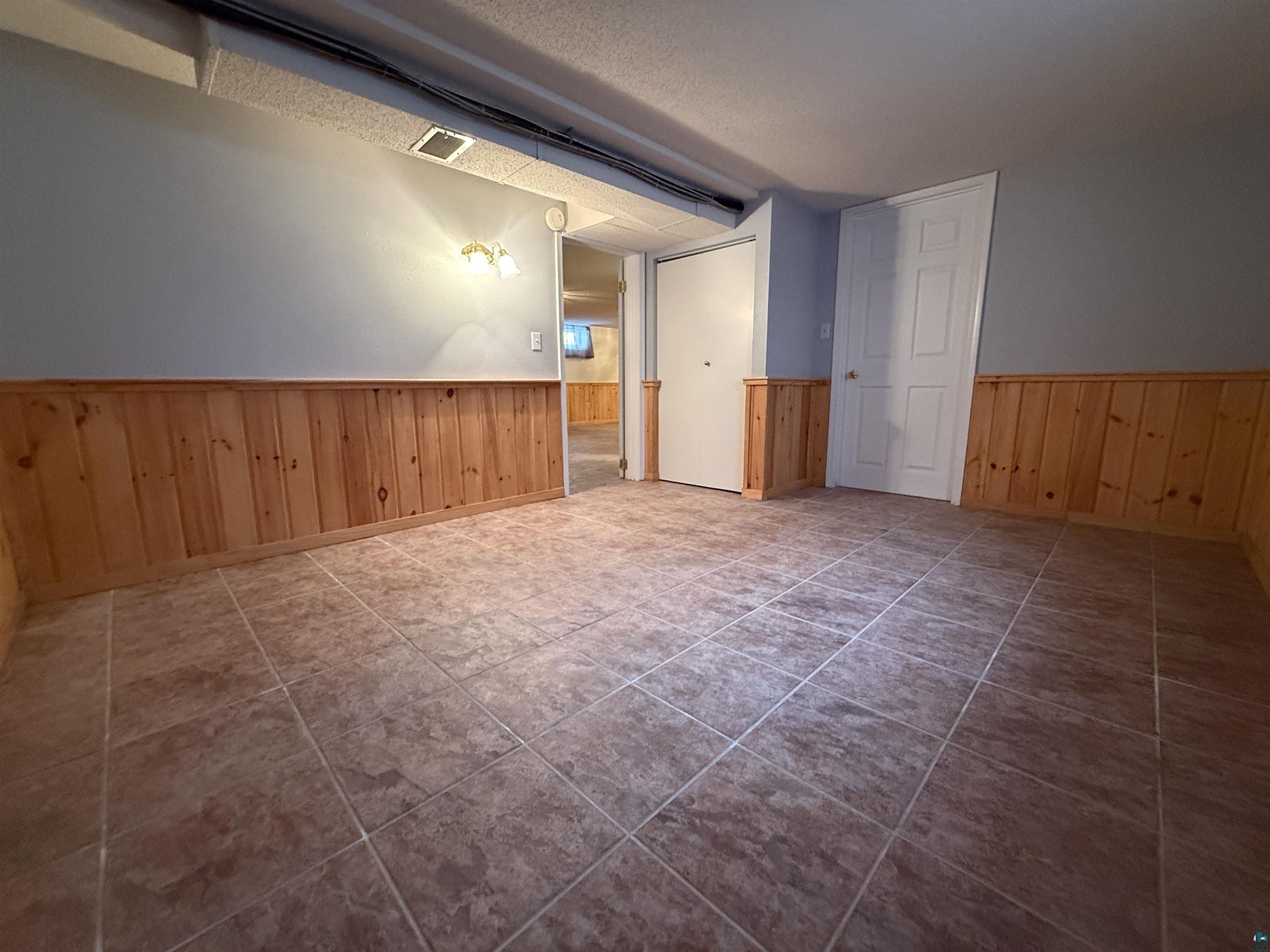 1321 South 13th Street Virginia, MN 55792 - Photo 24 of 33 Additional living space with wainscoting, wooden walls, and tile patterned flooring