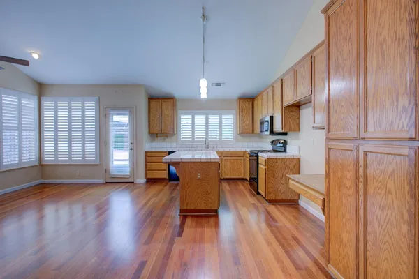 a living room with furniture dining table wooden floor and a large window