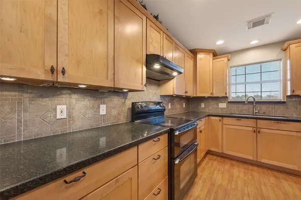 a kitchen with stainless steel appliances granite countertop a refrigerator and white cabinets