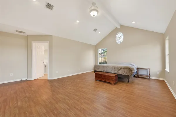 a spacious bedroom with a large bed and a wooden floor