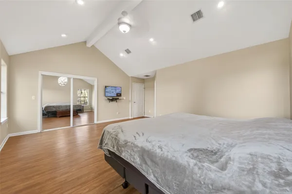 a spacious bedroom with a bed and a flat screen tv