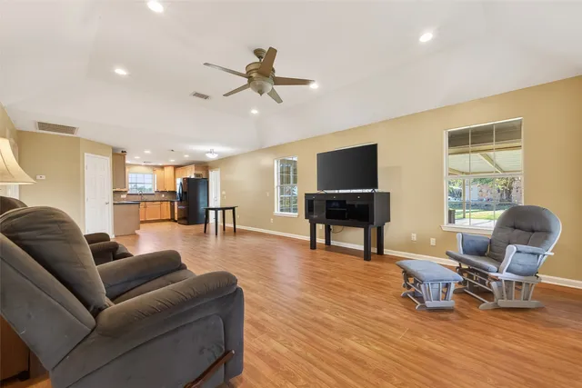 a living room with furniture and kitchen view with wooden floor