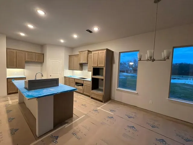 a kitchen with stainless steel appliances kitchen island granite countertop a sink refrigerator and cabinets