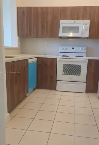 a kitchen with granite countertop a stove a sink and a white cabinets