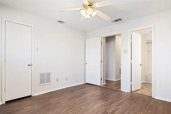 an empty room with wooden floor and a ceiling fan
