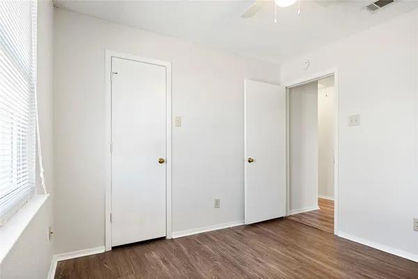 a view of an empty room with wooden floor and closet
