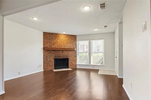 an empty room with wooden floor fireplace and windows