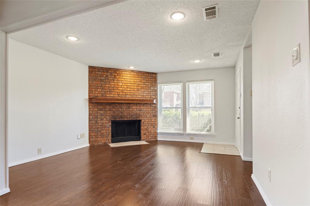 7591 Tournament Road Frisco, TX 75035 - Photo 4 of 26 an empty room with wooden floor fireplace and windows