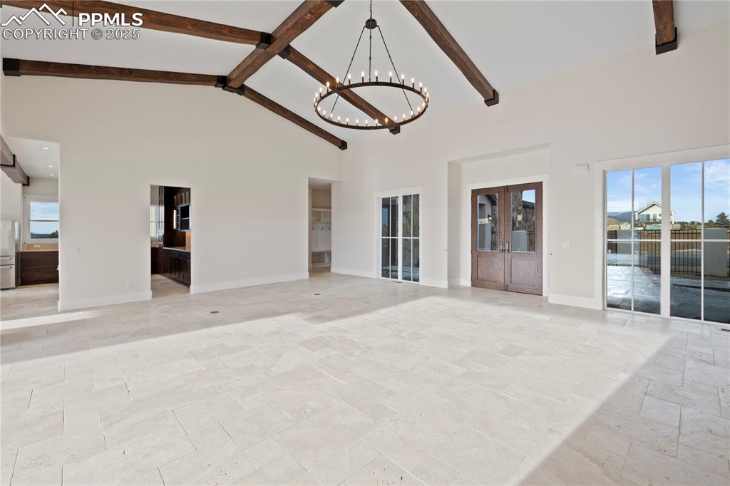 16864 Horizon Ridge Trail Colorado Springs, CO 80908 - Photo 16 of 47 Spare room with high vaulted ceiling, a chandelier, beamed ceiling, and plenty of natural light
