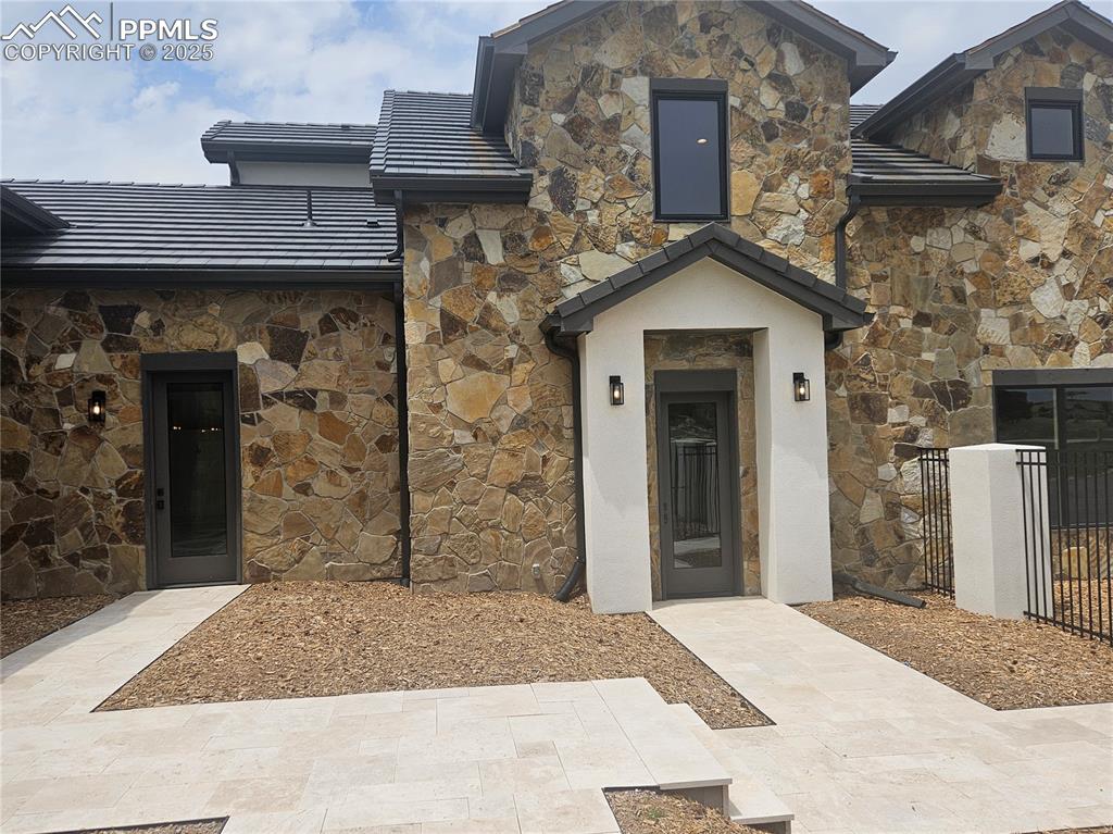 16864 Horizon Ridge Trail Colorado Springs, CO 80908 - Photo 5 of 47 View of exterior entry with stone siding, a tile roof, and stucco siding