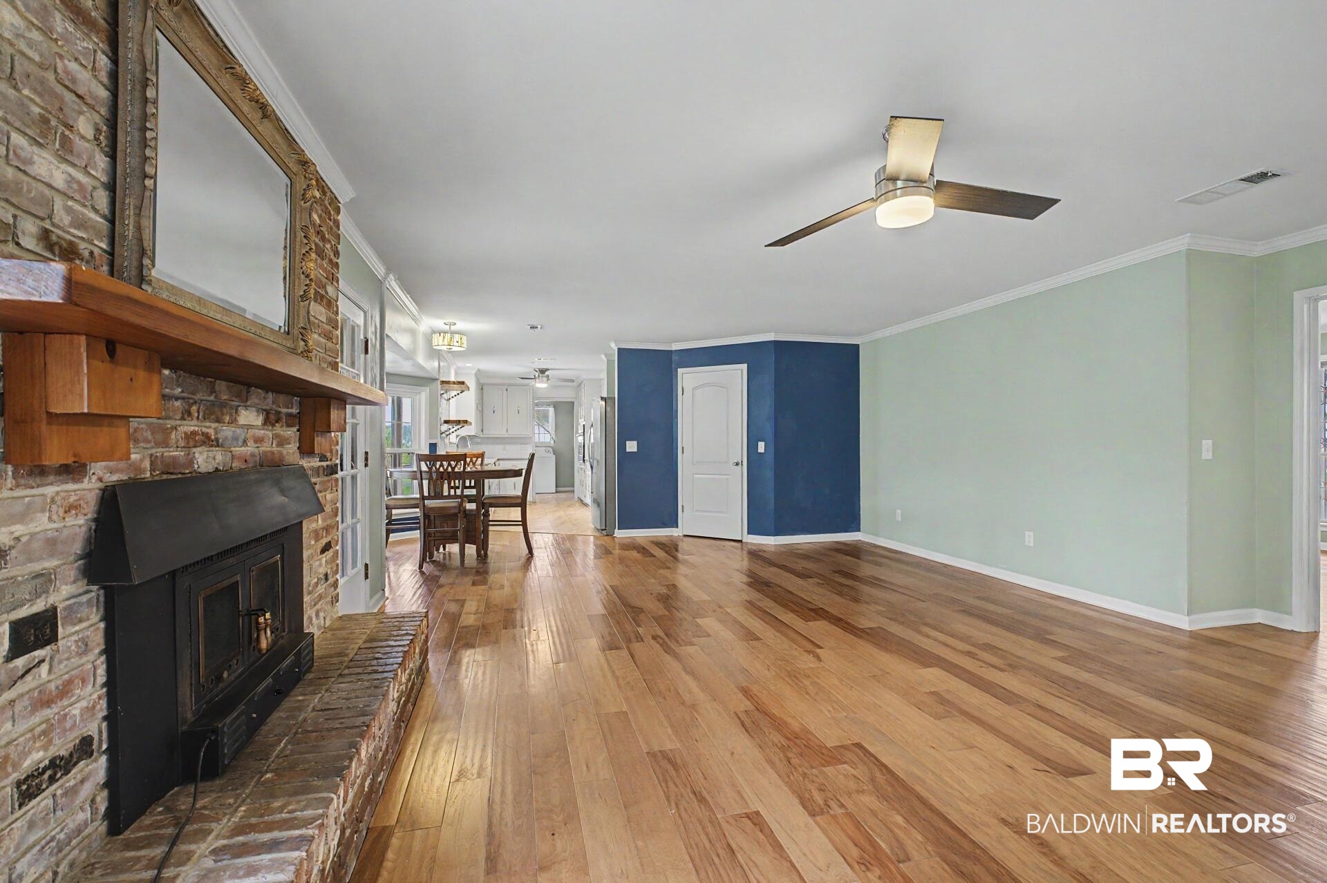 3791 Robinsonville Road Atmore, AL 36502 - Photo 31 of 47 Expansive living area featuring wood-finish flooring, a brick-surround fireplace with a wood mantle, and a ceiling fan