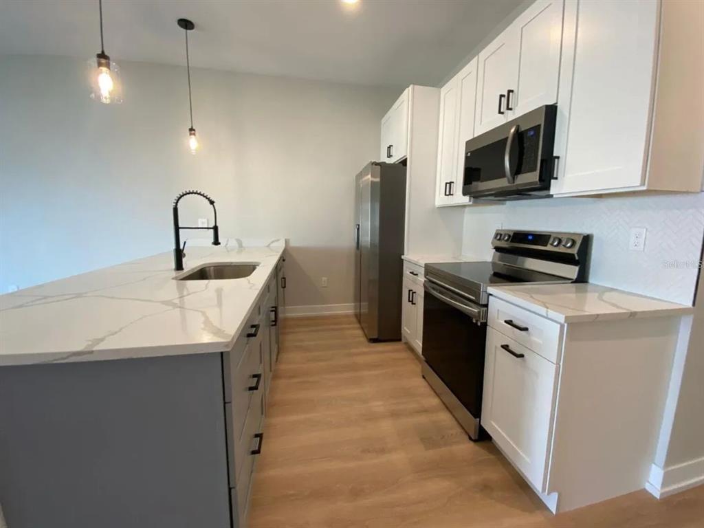10524 Pendleton Avenue Englewood, FL 34224 - Photo 3 of 12 a kitchen with stainless steel appliances granite countertop a sink a stove top oven and refrigerator