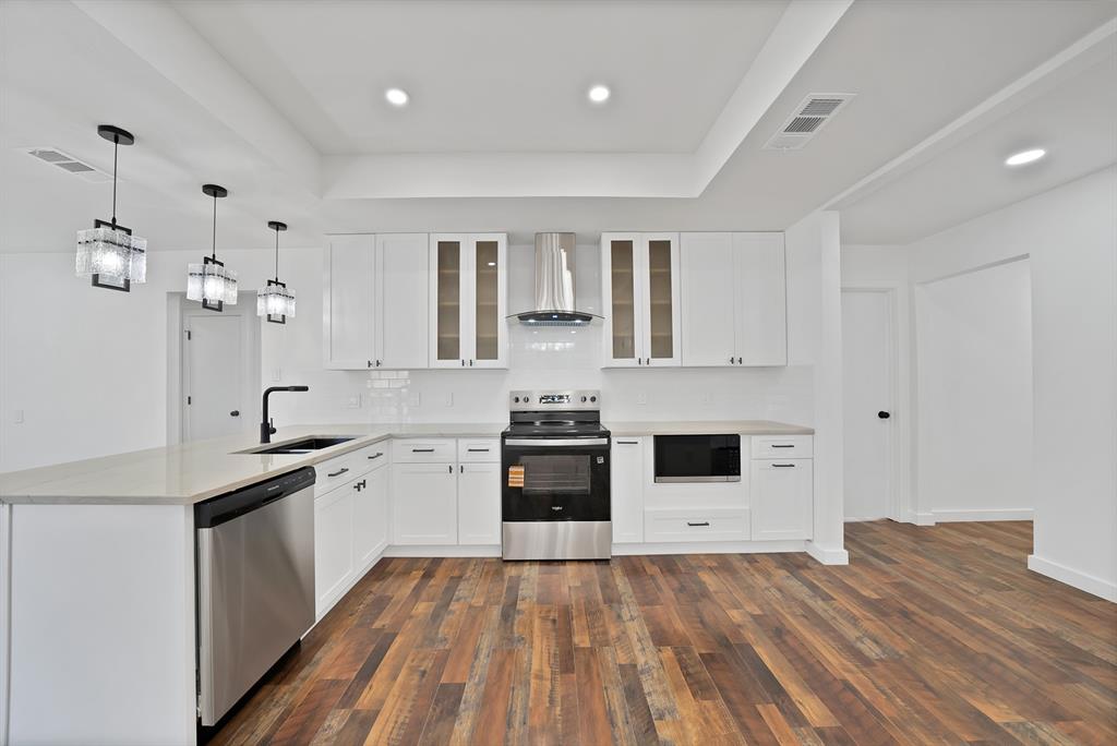 3410 Faulkner Drive Rowlett, TX 75088 - Photo 13 of 38 a large kitchen with granite countertop a stove top oven a sink a dishwasher and white cabinets with wooden floor