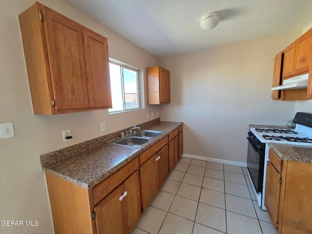 a kitchen with granite countertop a sink stove and cabinets