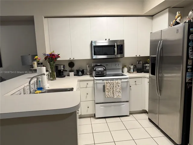 a kitchen with stainless steel appliances a refrigerator sink and white cabinets