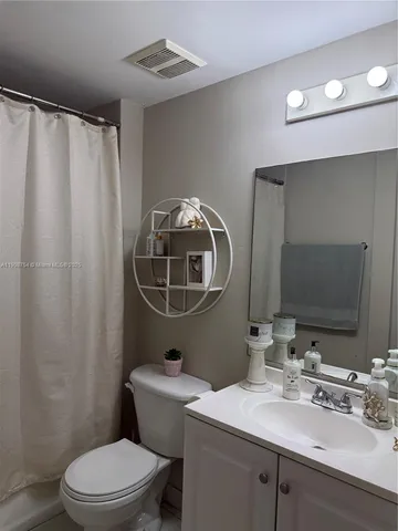 a bathroom with a sink vanity mirror and toilet