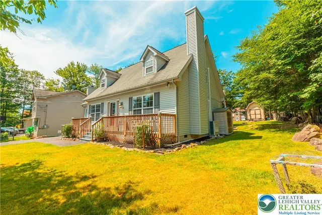 a view of a house with pool and chairs next to a yard