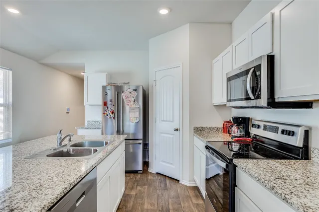 a kitchen with granite countertop a sink stove and refrigerator