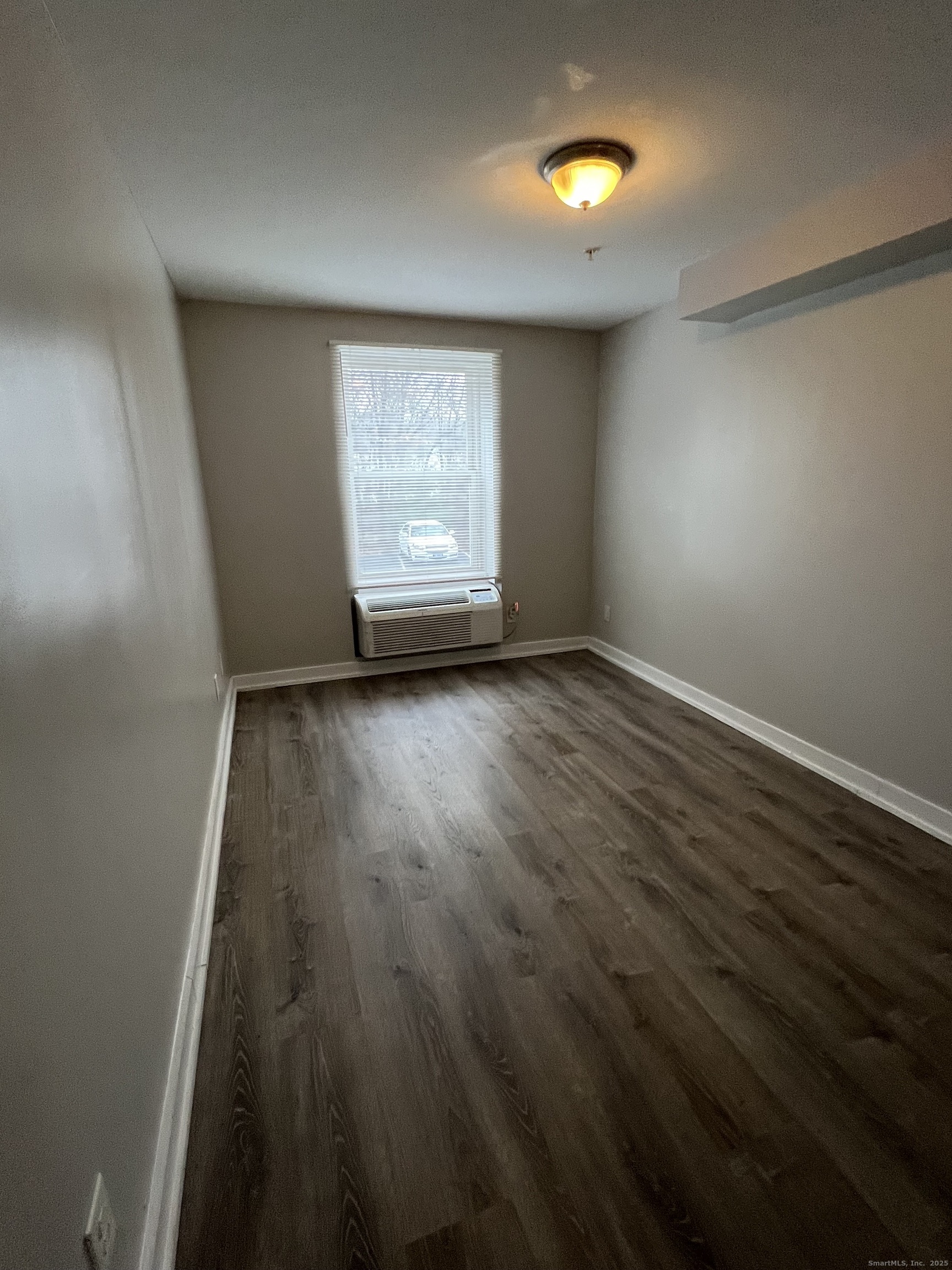 385 Putnam Avenue, Unit 5 Hamden, CT 06517 - Photo 5 of 13 an empty room with wooden floor and windows