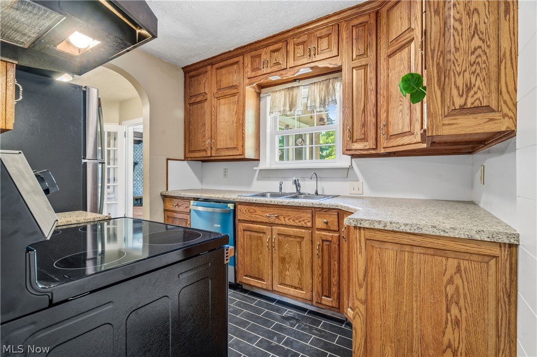 1769 Paradise Road Orrville, OH 44667 - Photo 10 of 36 Kitchen featuring wood cabinetry, light-colored countertops, a double basin sink, black tile flooring, and a black electric range