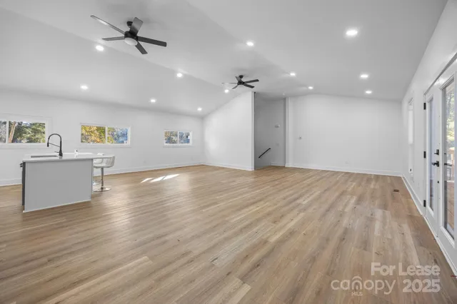 an empty room with wooden floor ceiling fan and windows