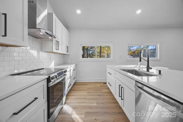 a large kitchen with stainless steel appliances granite countertop a lot of counter space and wooden floor
