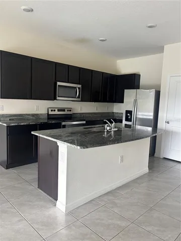 a kitchen with stainless steel appliances granite countertop a stove a sink and a microwave