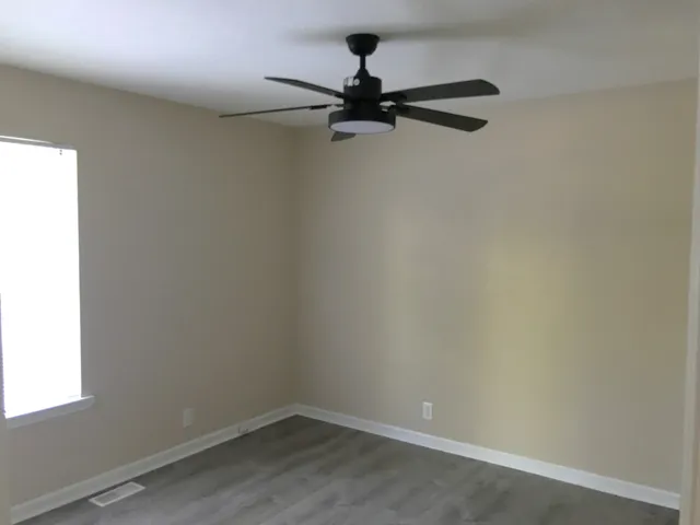 an empty room with a window and a fan