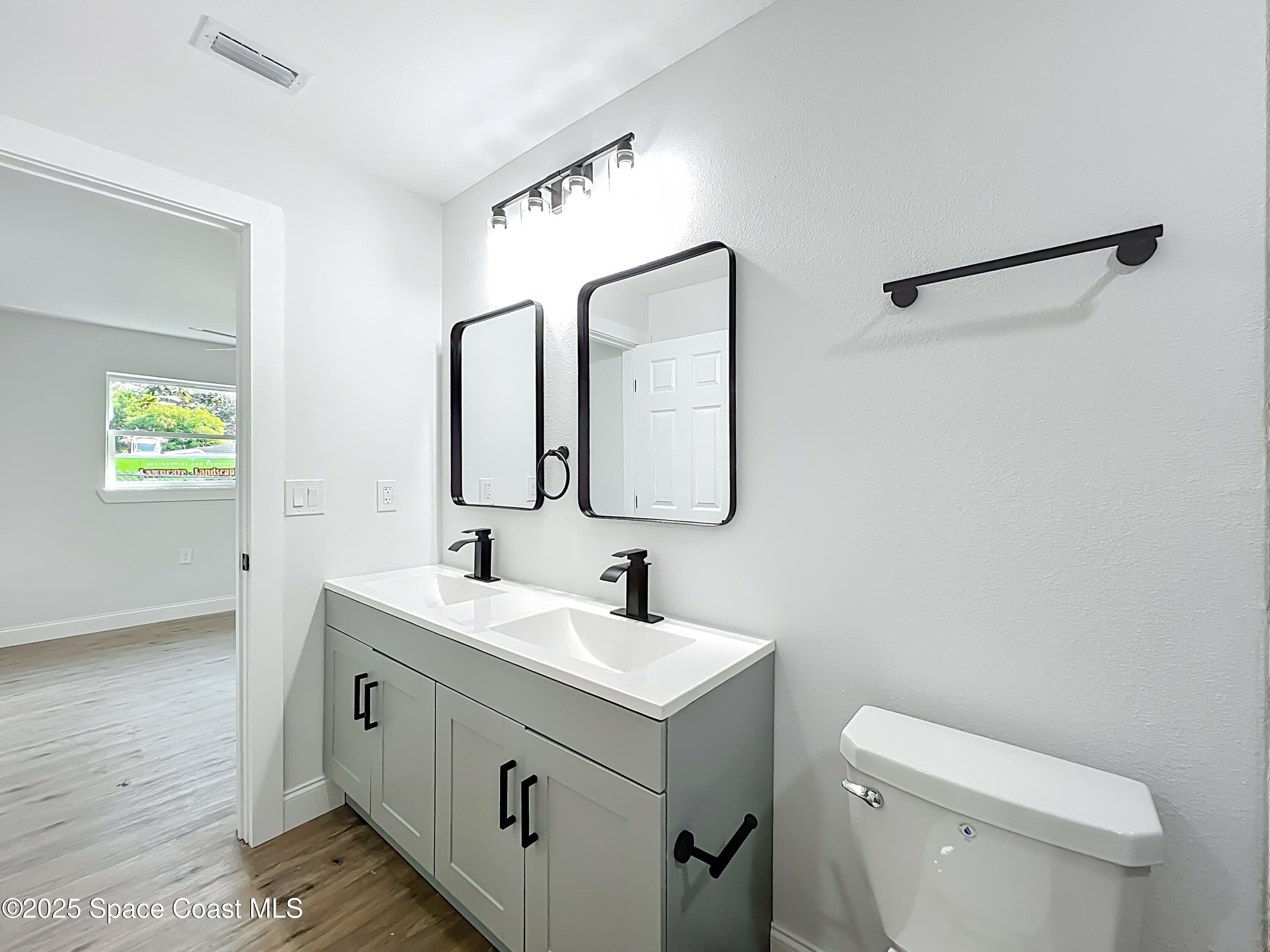 2340 Iowa Drive Melbourne, FL 32935 - Photo 15 of 47 a bathroom with a toilet a sink a mirror and a window