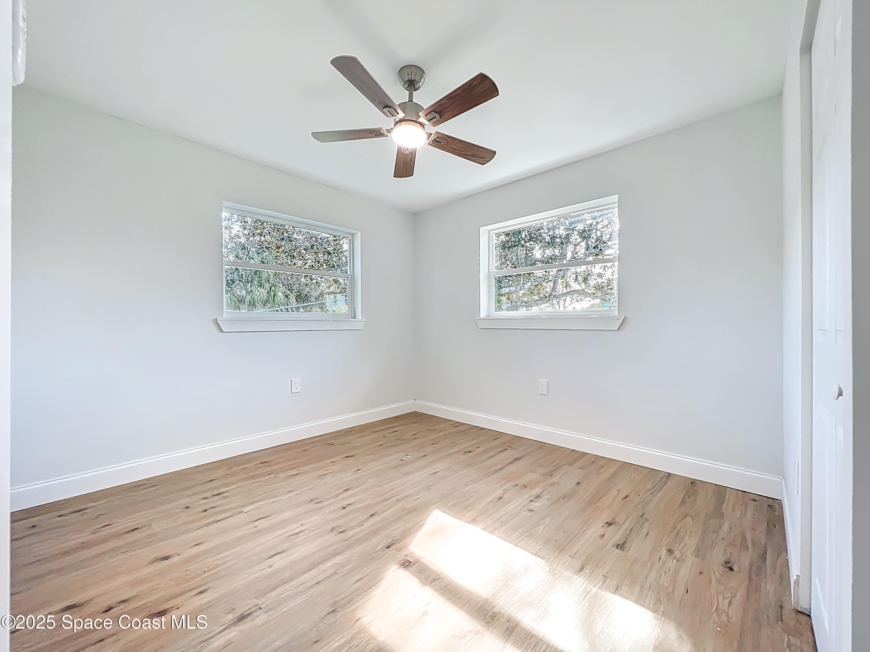 2340 Iowa Drive Melbourne, FL 32935 - Photo 31 of 47 a view of an empty room with wooden floor and a ceiling fan