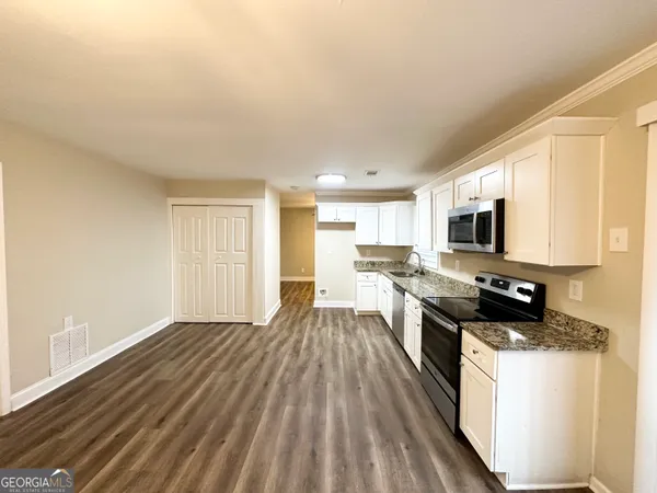 a kitchen with stainless steel appliances a stove top oven a sink dishwasher and a microwave with wooden floor