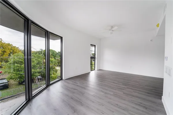 a view of an empty room with wooden floor and a window
