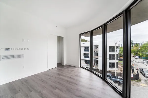 a view of an empty room with wooden floor and a window