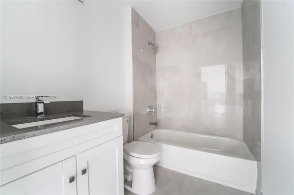 a bathroom with a granite countertop sink a toilet and bathtub