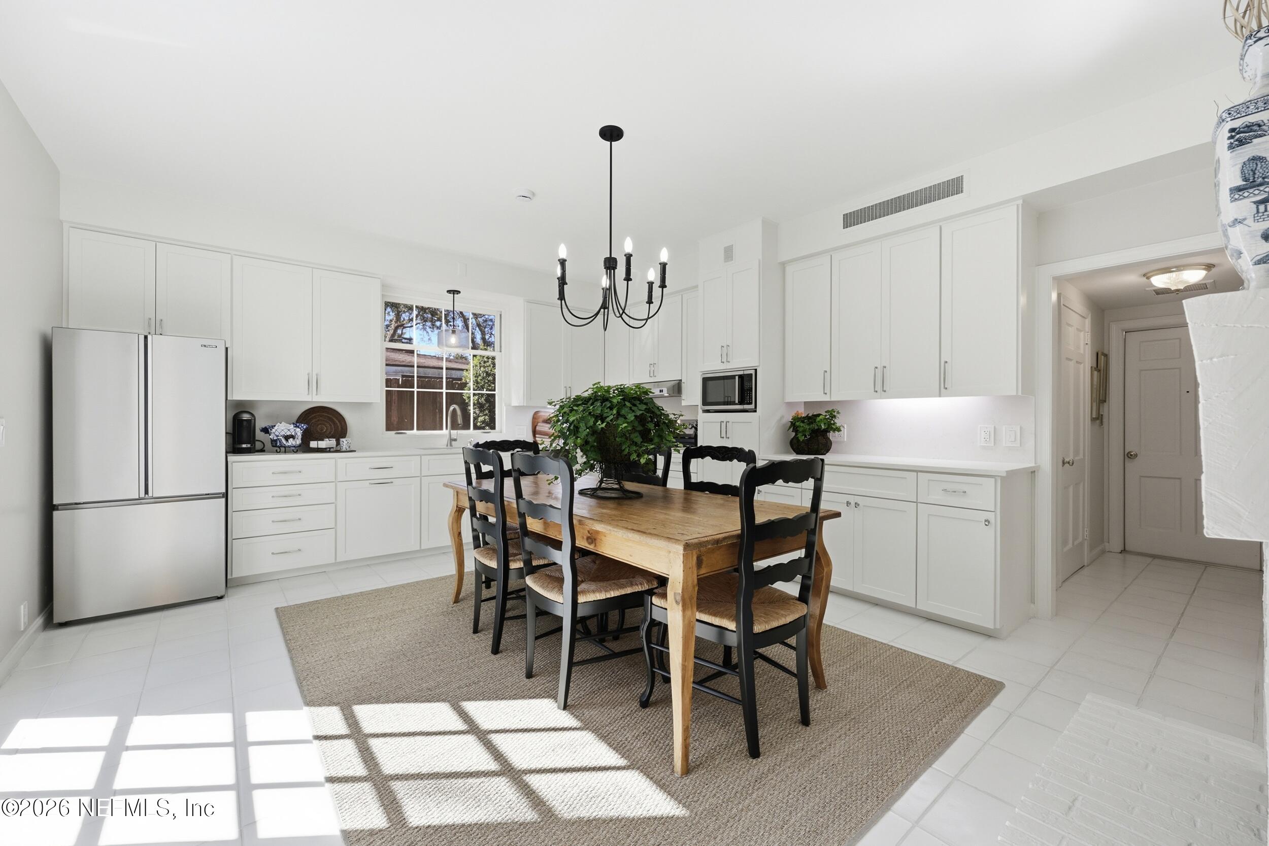 4706 Ivanhoe Road Jacksonville, FL 32210 - Photo 15 of 47 a kitchen with a refrigerator a dining table and chairs