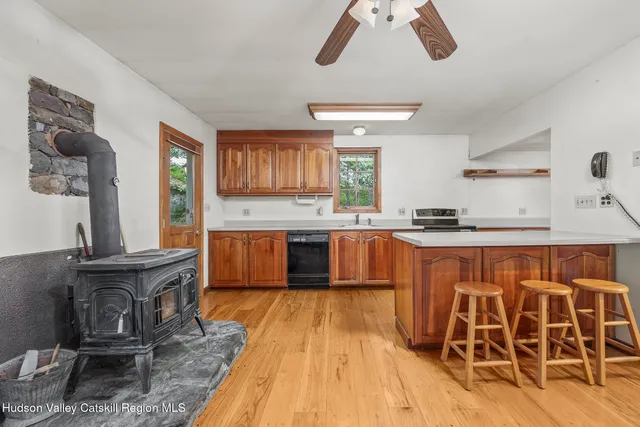 a open kitchen with stainless steel appliances kitchen island granite countertop a stove top oven a dining table and chairs with wooden floor