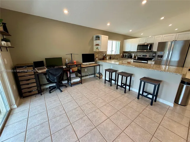 a living room with furniture a flat screen tv and kitchen view